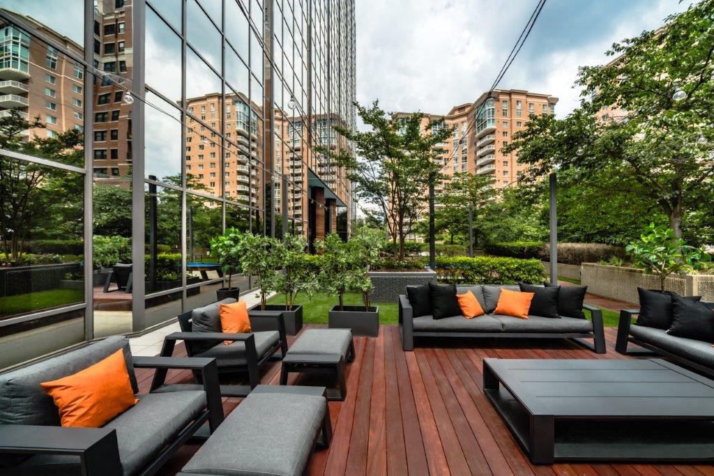 a lounge area with couches and chairs on a deck in front of a building