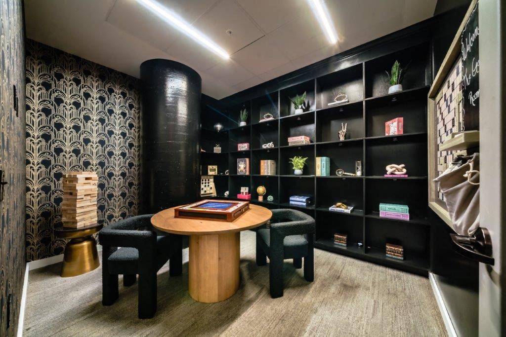 a room with a table and chairs in front of a book shelf