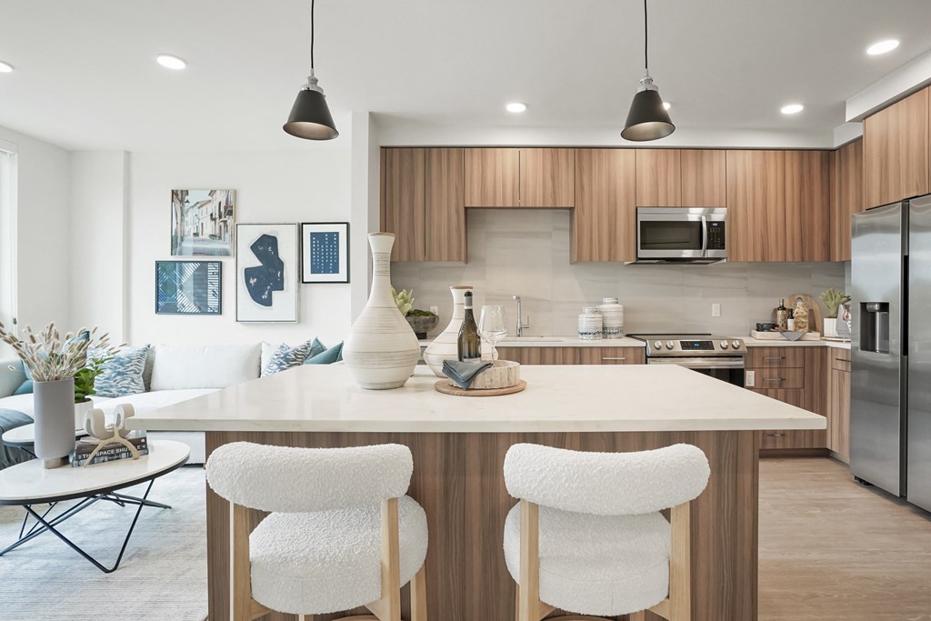 an open kitchen and living room with a large island with three chairs