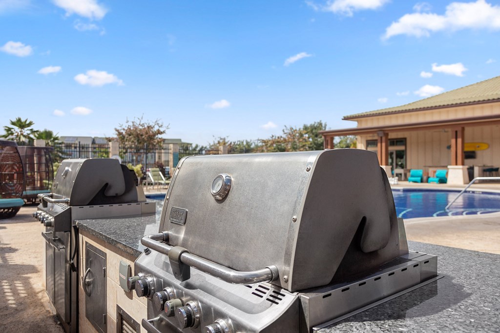 two bbq grills next to a swimming pool