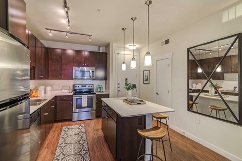 A modern kitchen with dark wood cabinets and stainless steel appliances.