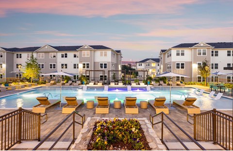 an outdoor swimming pool with lounge chairs and umbrellas at an apartment complex