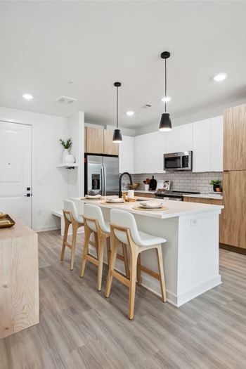 a kitchen with white cabinets and a large island with chairs