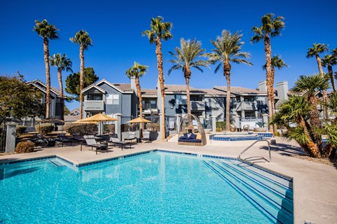A resort-style pool surrounded by palm trees and lounge chairs at The Layne at Peccole Ranch modern apartments in Las Vegas.