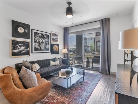 A living room with a black couch, a chair, a coffee table, and pictures on the wall.