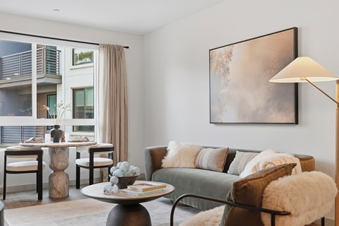 A living room with a grey couch, a coffee table, and a large painting on the wall.