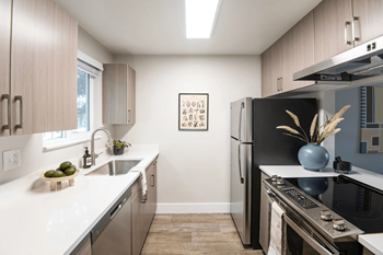 A kitchen with a black refrigerator and a framed picture on the wall.