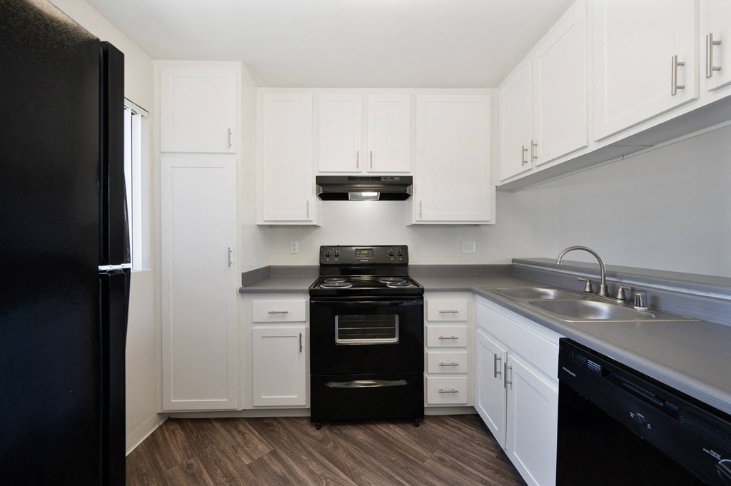 a 1-bedroom apartment kitchen with white cabinets and black appliances and a sink