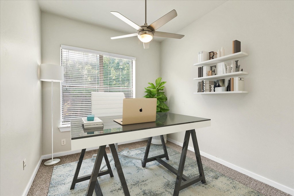 a home office with a ceiling fan and a laptop on a desk