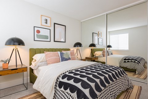 Bedroom with green upholstered headboard and mirrored closet at Brookside112 Apartments, Washington