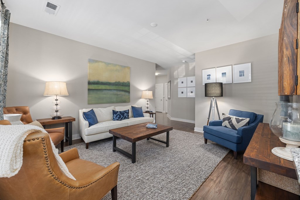 A living room with a white couch, a brown chair, and a painting on the wall.