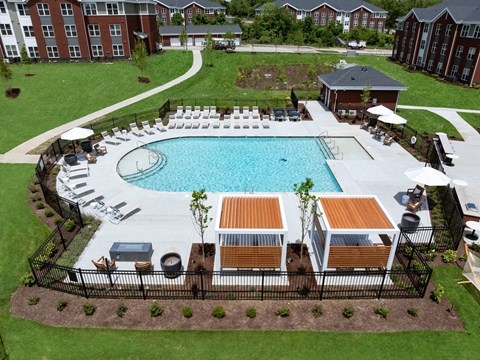 A pool surrounded by a black fence with a small tree in the middle.