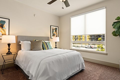 A bedroom with a large bed and a window overlooking a street.