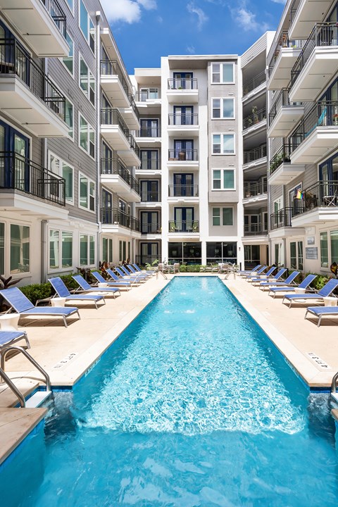 A large swimming pool in front of a multi-story residential building.