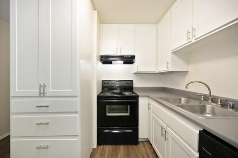 a kitchen with white cabinets and a black oven and sink