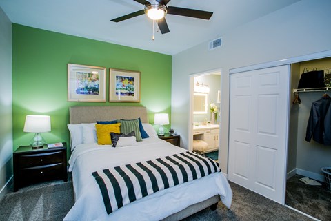 A modern bedroom with a bed, nightstands, and ceiling fan at The Layne at Peccole Ranch modern apartments in Las Vegas.