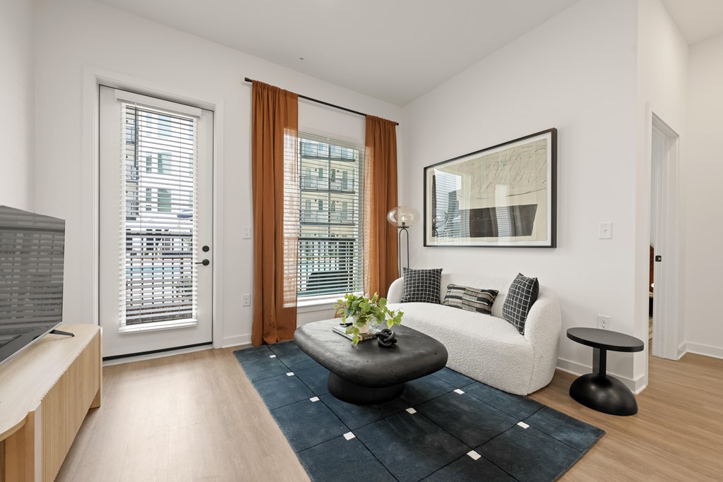 A living room with a couch, a coffee table, and a large window.