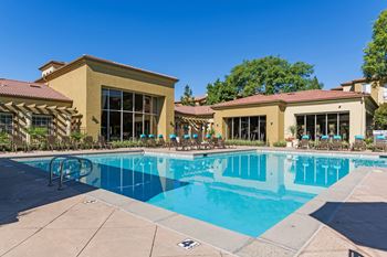 A large swimming pool in front of a building with a red tile roof.