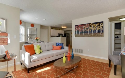 A living room with a white couch and orange pillows.