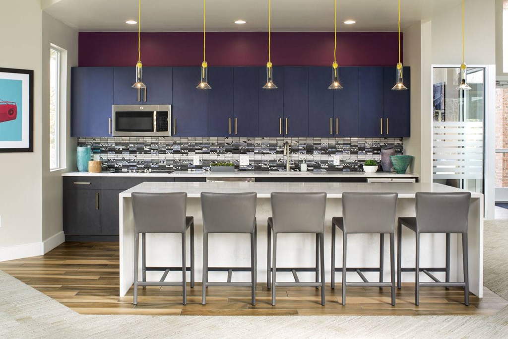 A kitchen with a bar area and grey chairs.