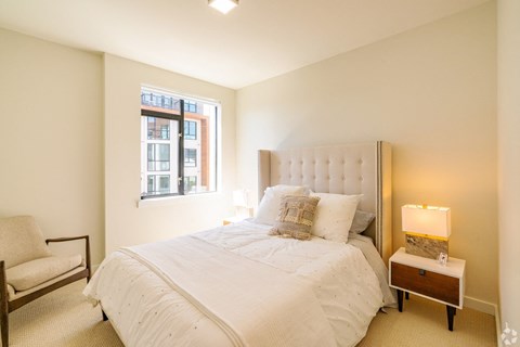 A bedroom with a large bed and a chair.