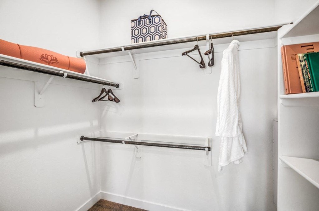a walk in closet with white walls and a white robe hanging on the wall