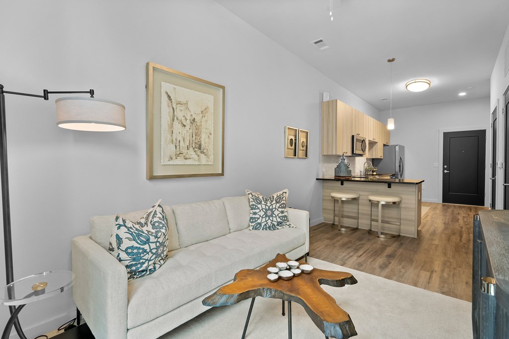a living area with a couch coffee table and a kitchen in the background