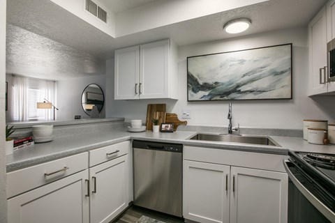 A modern kitchen with white cabinets and a marble painting on the wall.