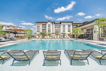 a swimming pool with lounge chairs and buildings in the background