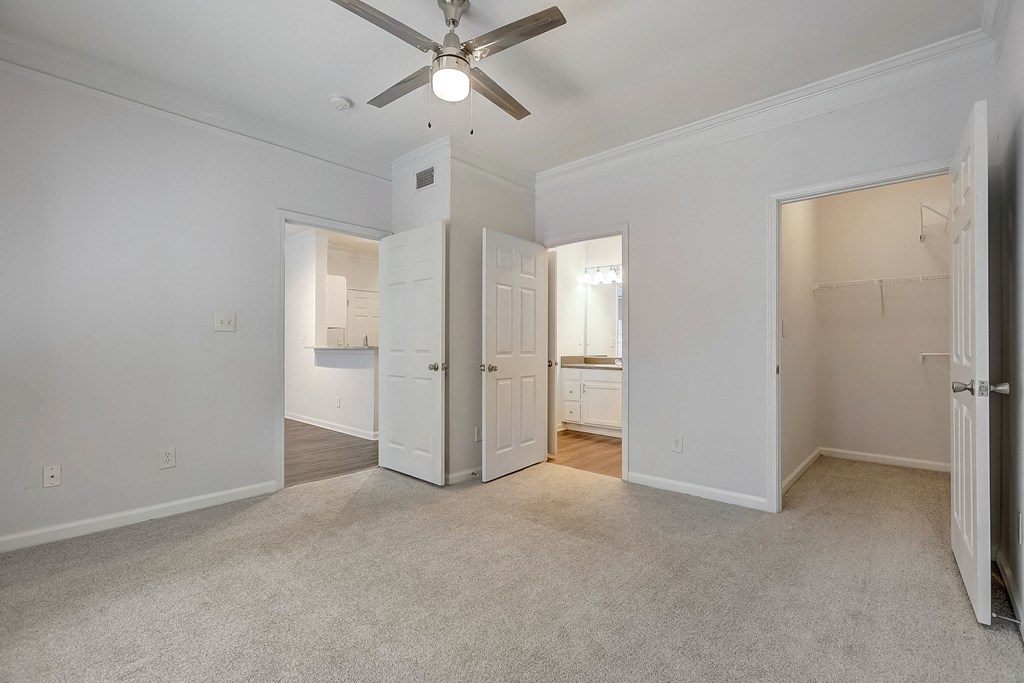 a bedroom with white walls and a ceiling fan