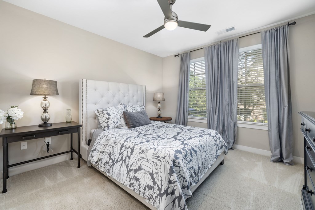 A bedroom with a large bed and a ceiling fan.
