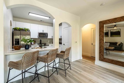 A kitchen with a counter and chairs.