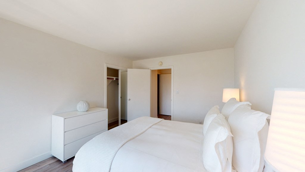 a bedroom with a large white bed and a white dresser