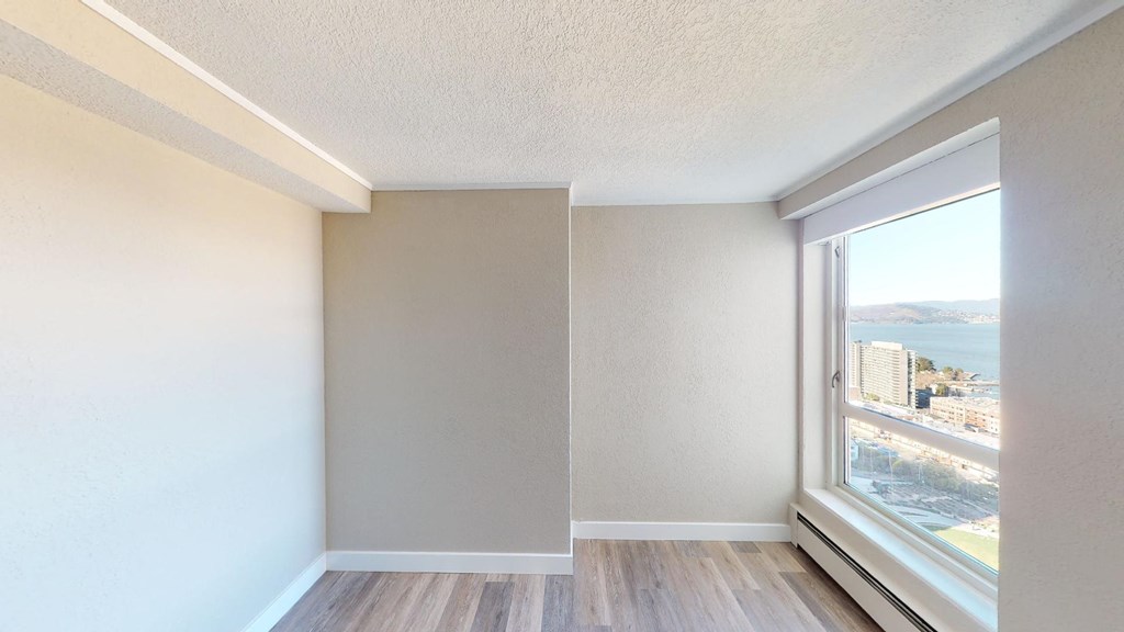 an empty room with a large window and hardwood floors