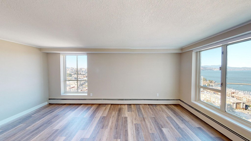 an empty living room with large windows and hardwood floors