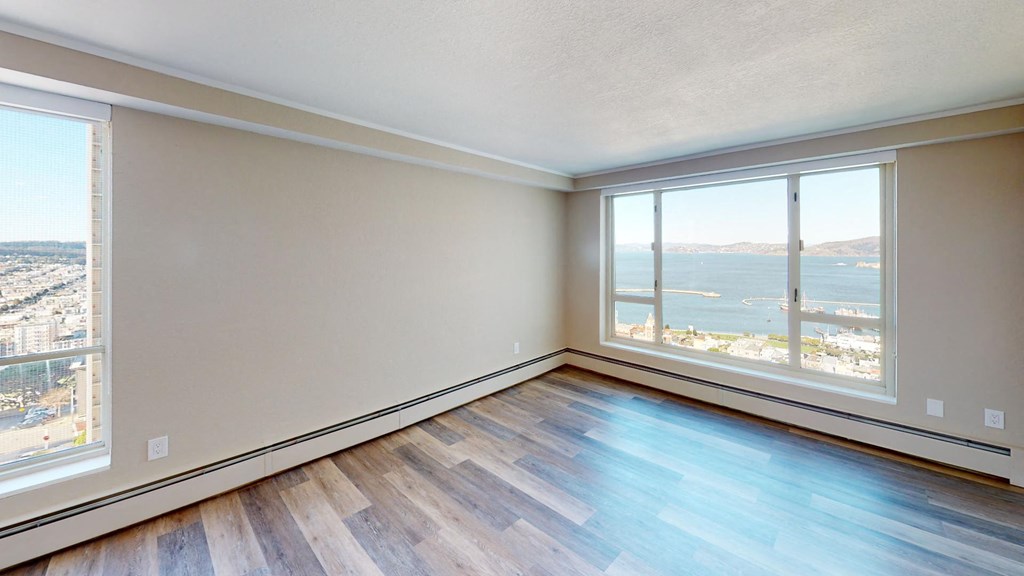 an empty living room with a large window and a view of the water