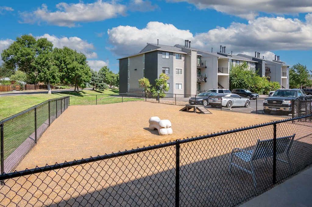 a fenced in dog park with apartments in the background