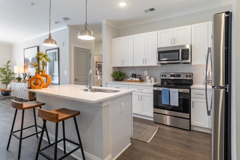 A modern kitchen with white cabinets and stainless steel appliances.