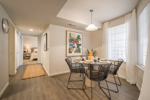 A dining room with a table set for two and a painting on the wall.