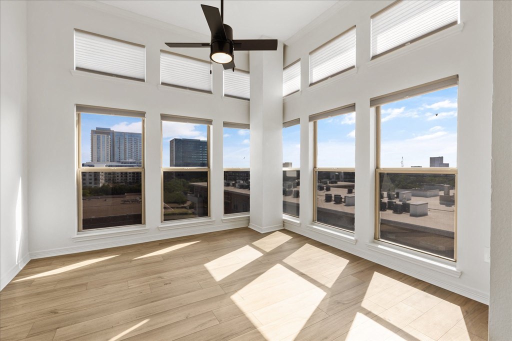 an empty living room with windows and a ceiling fan