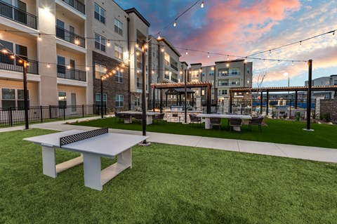 A white table is in the middle of a grassy area with apartment buildings in the background.