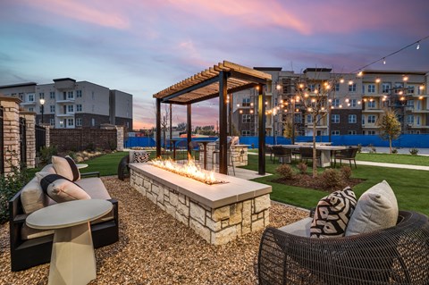 A patio with a fire pit and chairs.
