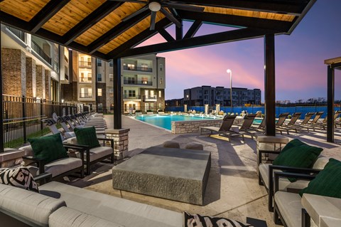 A poolside area with lounge chairs and a view of a residential building.