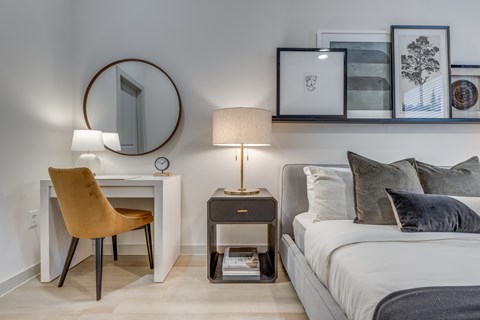 A bedroom with a bed, a chair, a nightstand, and a mirror.