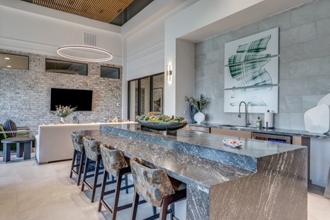 A modern kitchen with a marble countertop and bar stools.