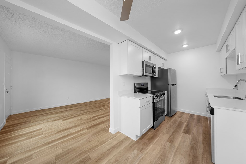 A kitchen with white cabinets and a wooden floor.