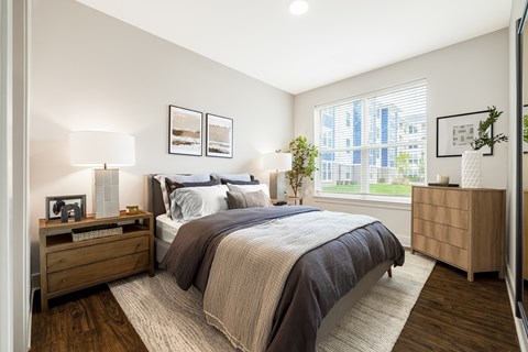 A bedroom with a large bed and a window overlooking a cityscape.
