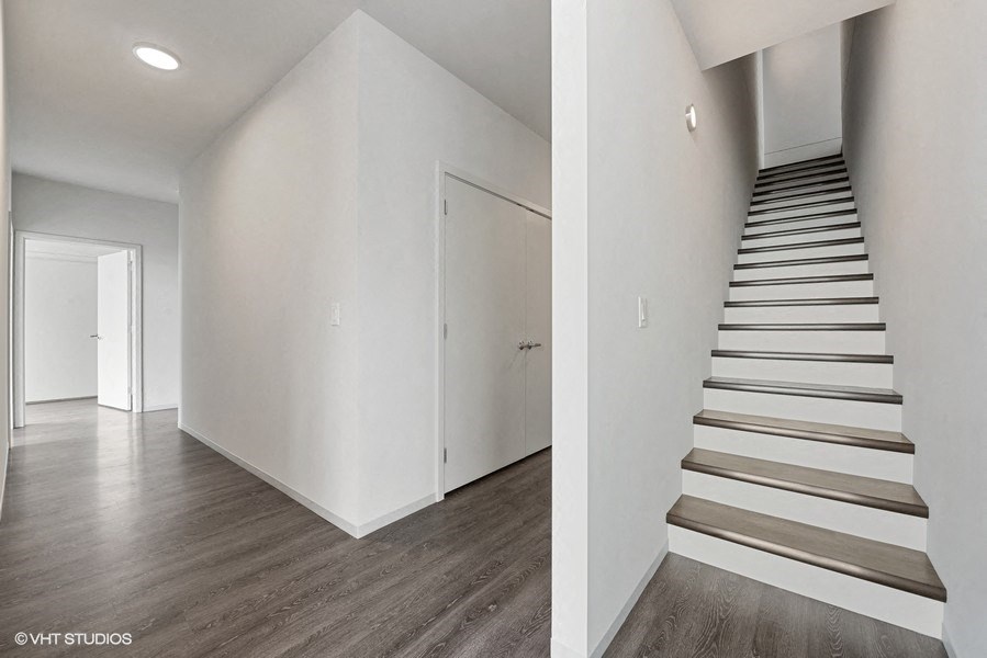 a large white room with a staircase and a white door and a hallway with stairs