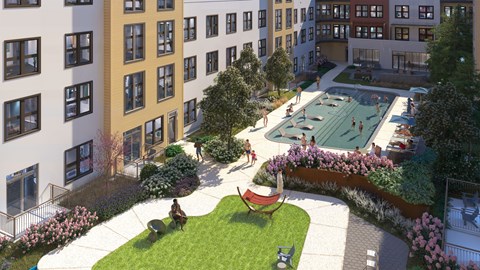 A pool surrounded by a grassy area with people in it.