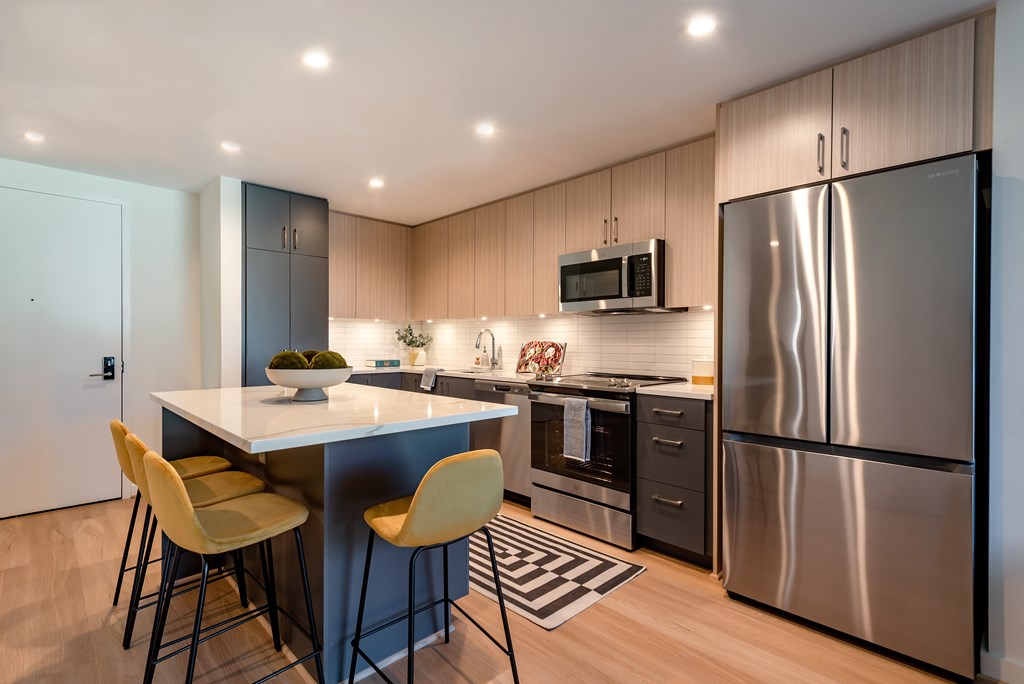 A modern kitchen with a large island and stainless steel appliances.